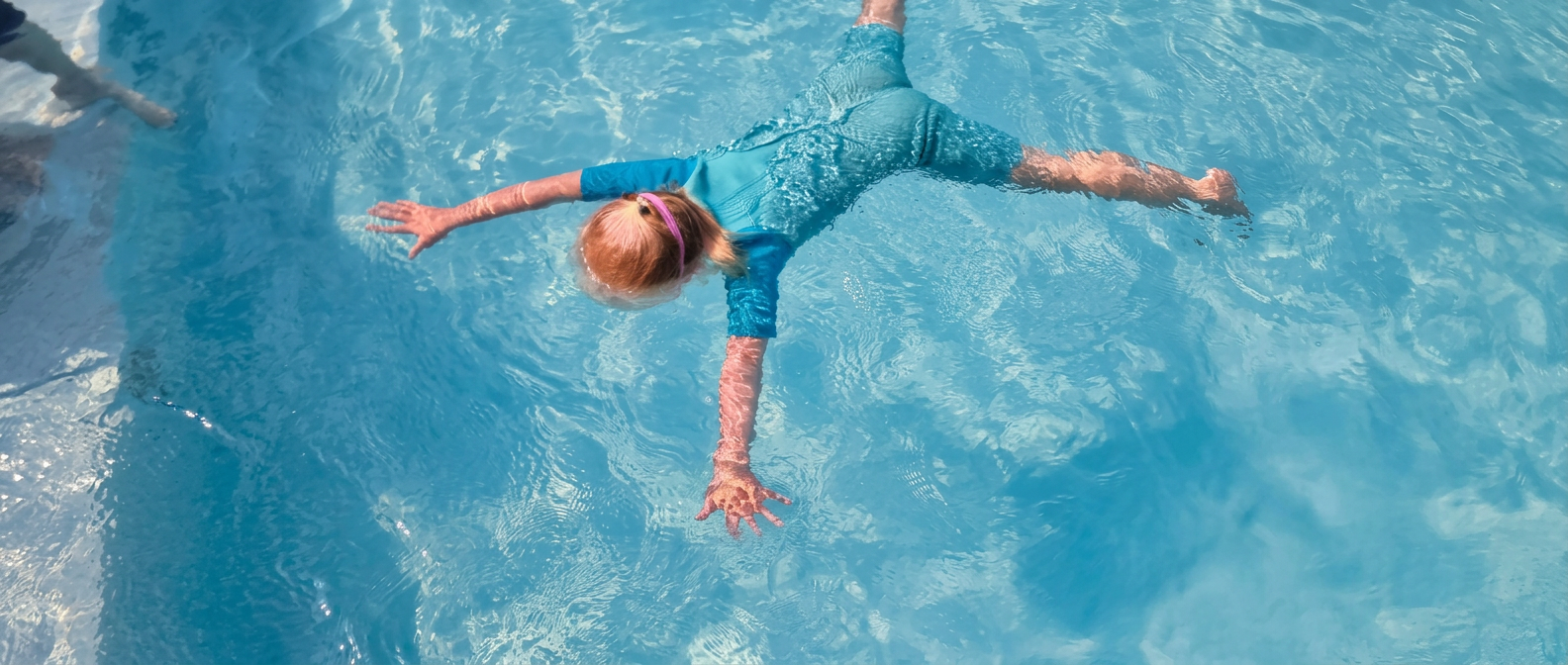 Meisje dat als een ster op het water drijft in het buitenzwembad