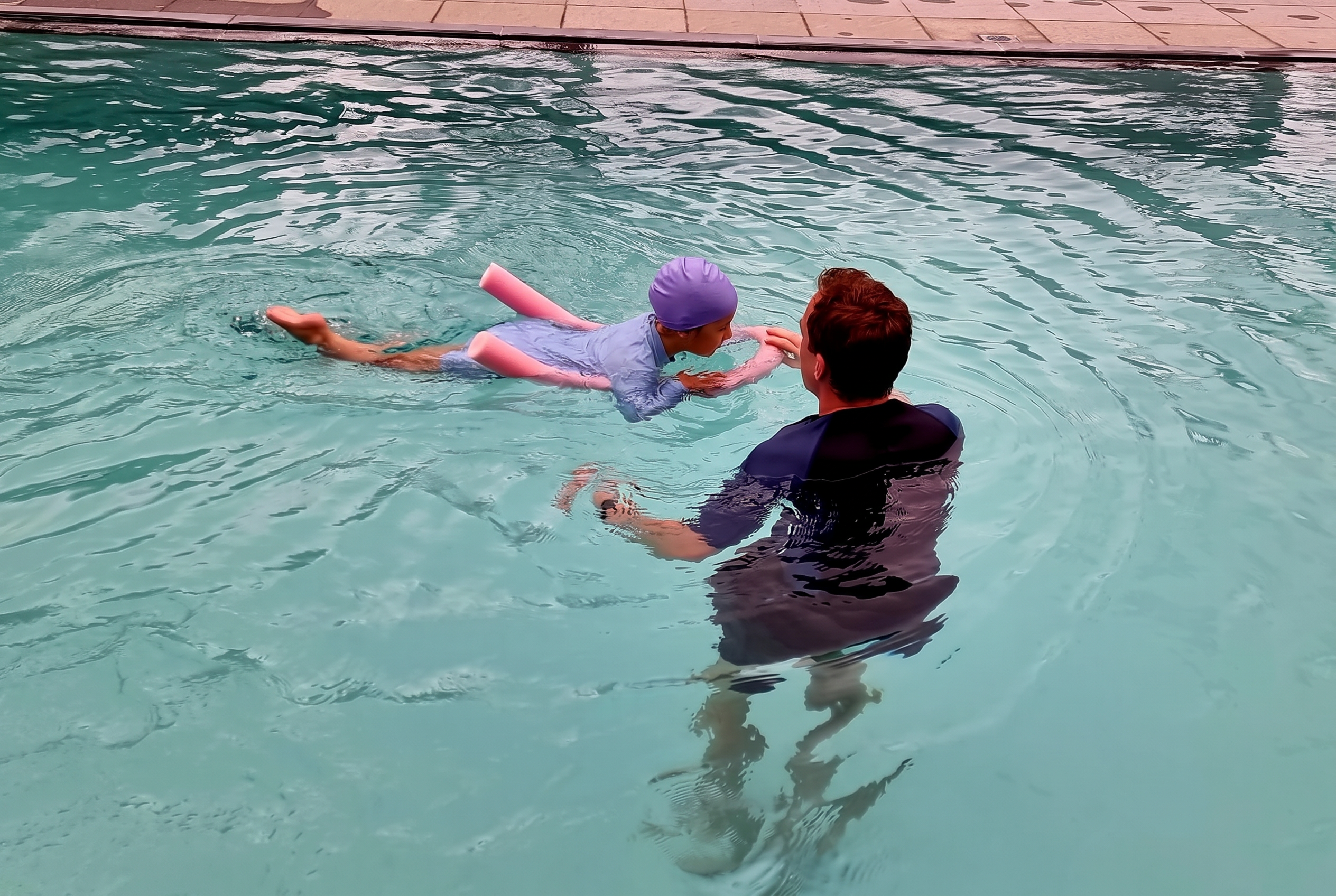 Joppe De Feyter staat in het water en begeleidt een kind dat met een noodlijn drijft