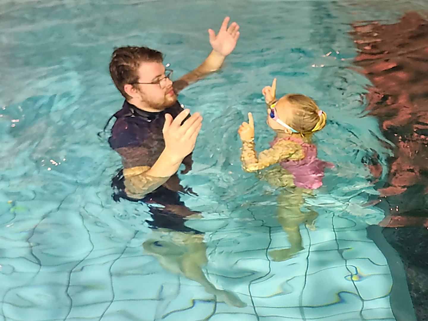 Jorne Hillen begeleidt een peuter in het water terwijl ze samen naar boven wijzen